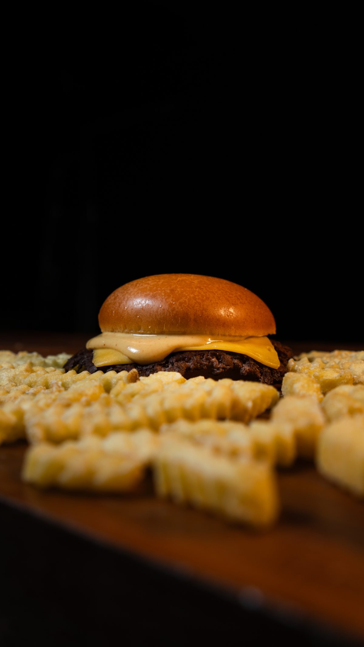 Cheeseburger com batatas crinkle em fundo escuro