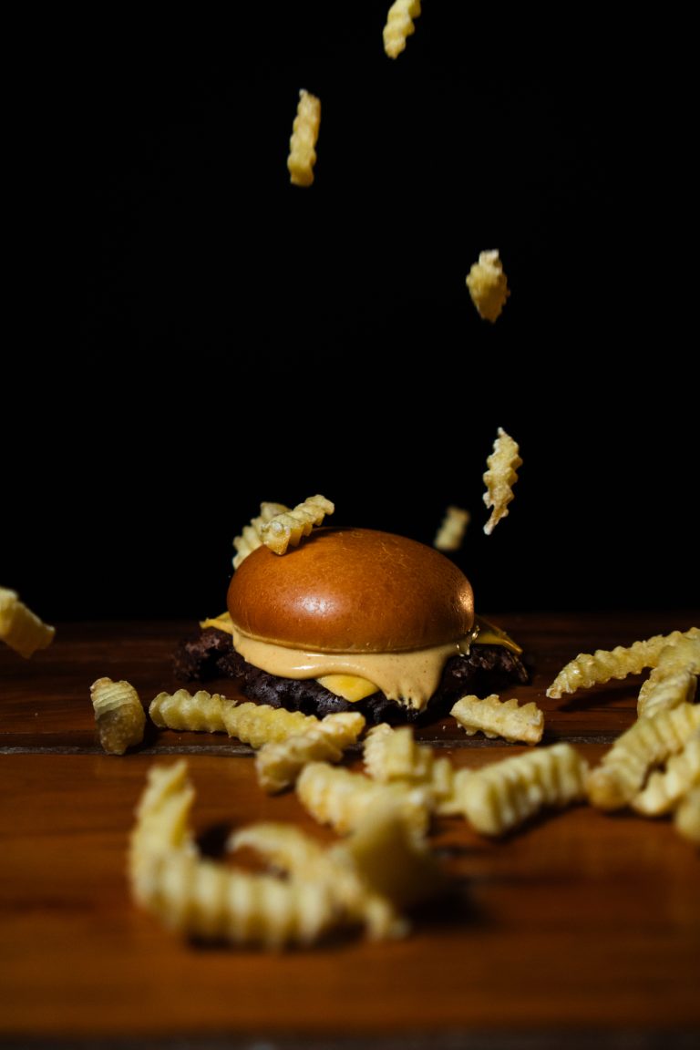 Smash burger com batatas crinkle em fundo preto